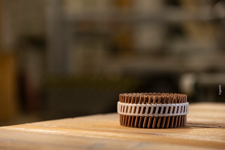 Ein Coil LIGNOLOC® Holznägel von BECK liegt auf einer Holzwerkbank.