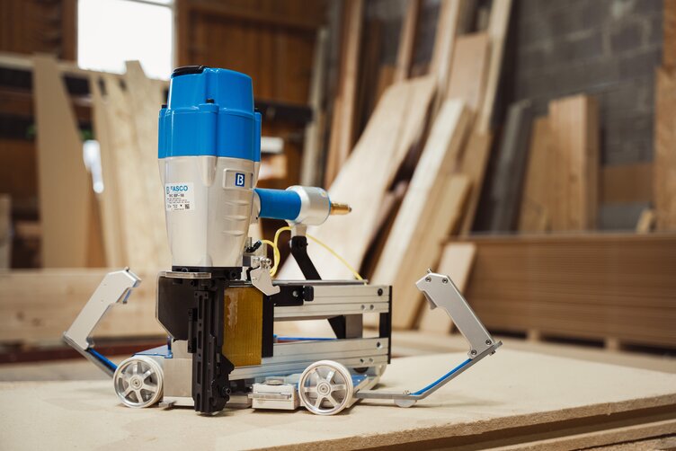 The FASCO® INMOTION handheld sled on a wooden wall together with a BECK nailer.