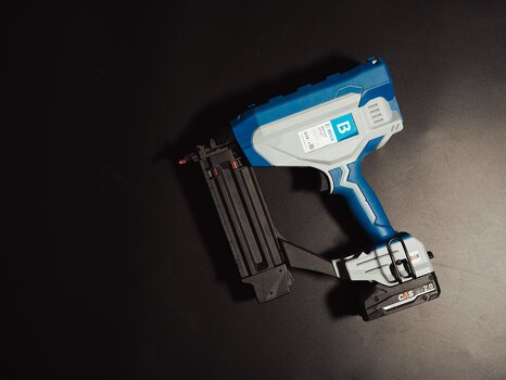 BECK battery-powered brad nailer lying on black background.