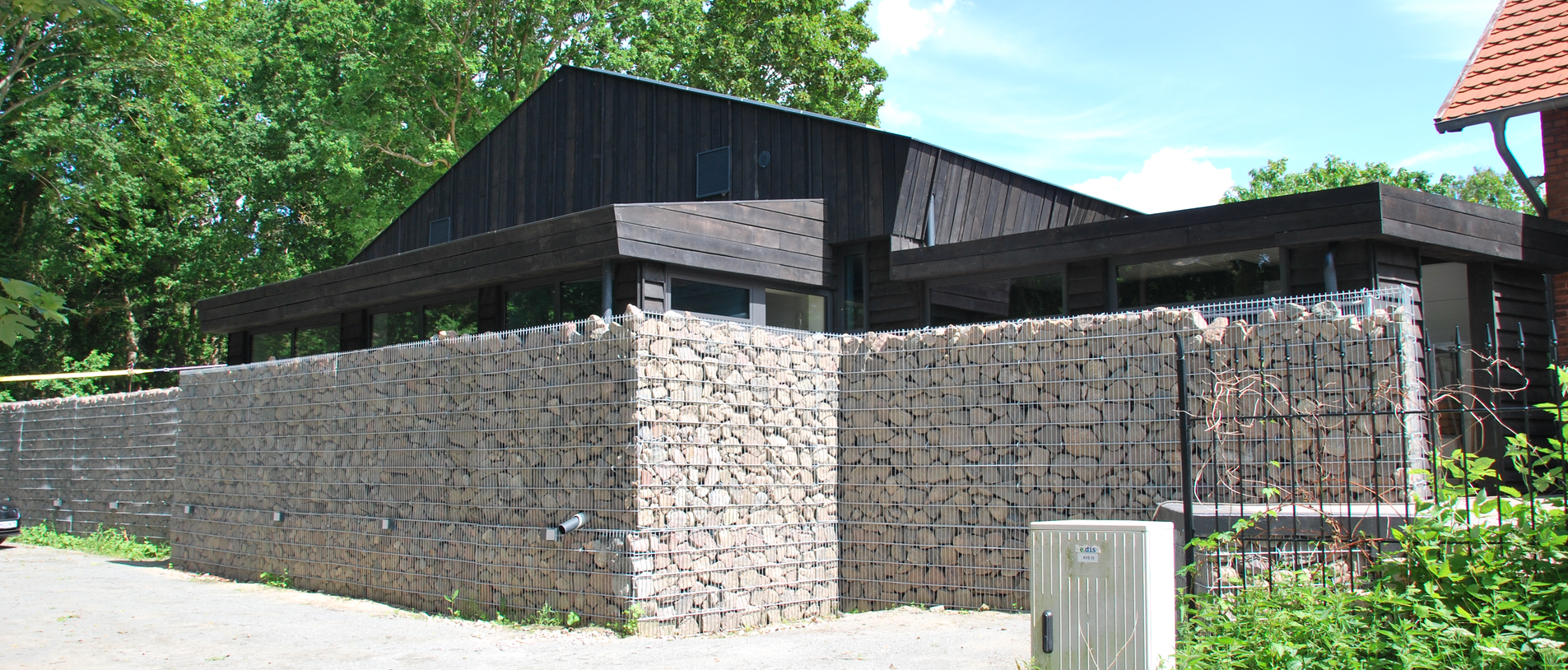 Tanzschule am Eichberg – Außenansicht mit dunkler Holzfassade und Gabionenwand, umgesetzt mit LIGNOLOC® Holznägeln von BECK