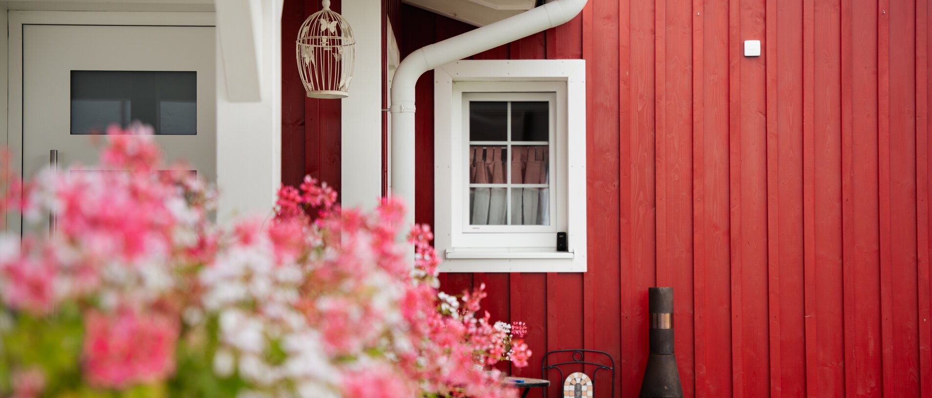 Norwegerhaus – Fensterdetail | BECK Norwegerhaus – Detailaufnahme der roten Holzfassade mit weißem Fensterrahmen, realisiert mit LIGNOLOC® Holznägeln von BECK