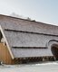 Bauernbogen Abtenau – Außenansicht mit geschwungenem Bogendach und vertikaler Holzfassade, realisiert mit LIGNOLOC® Holznägeln von BECK