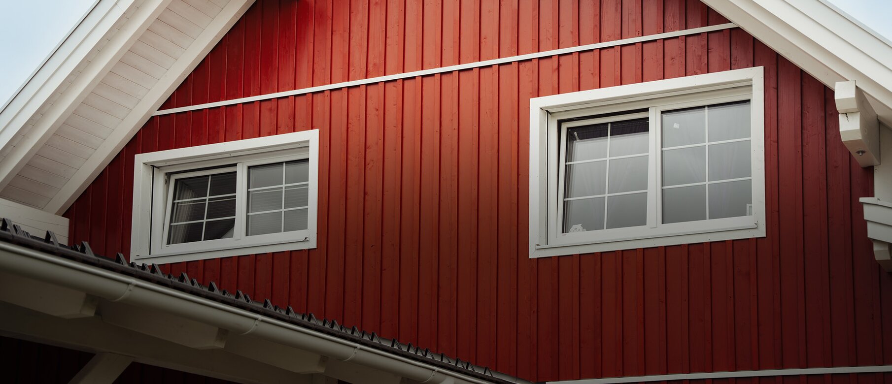 Norwegerhaus – Außenansicht | BECK Norwegerhaus – Außenansicht mit roter Holzfassade in Boden-Deckel-Schalung, befestigt mit LIGNOLOC® Holznägeln von BECK