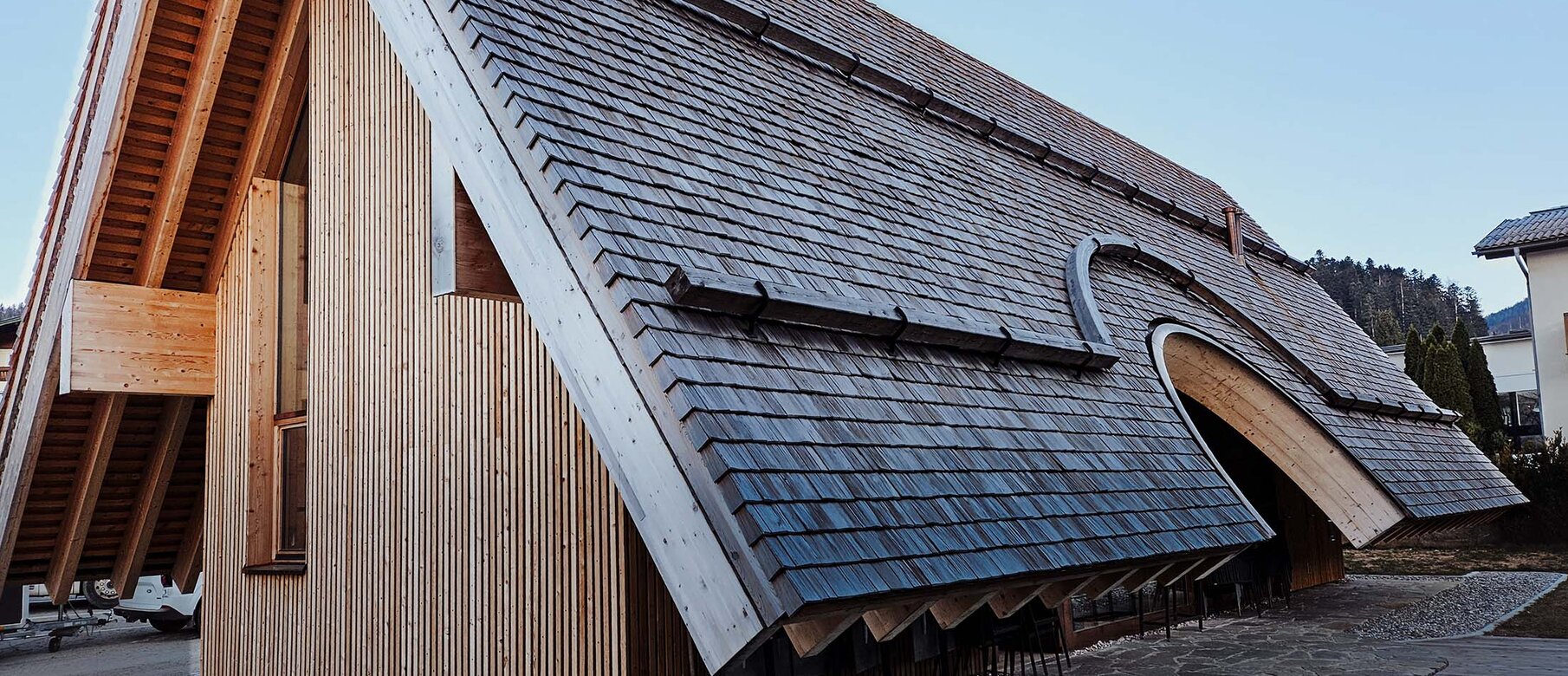 Bauernbogen Abtenau – Frontansicht mit geschwungenem Dach und vertikaler Holzfassade, befestigt mit LIGNOLOC® Holznägeln von BECK